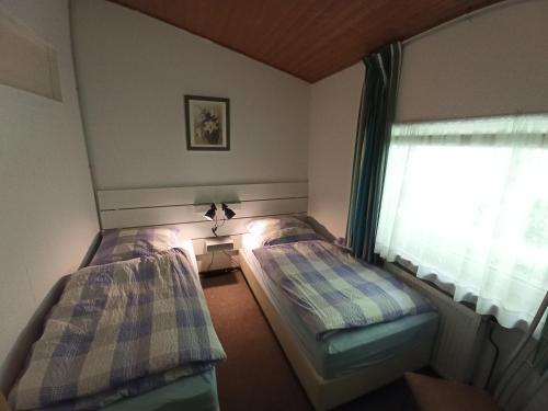 two beds in a room with a window at Ferienhaus D51 Europa Feriendorf 2-5 Personen in Lichtenau