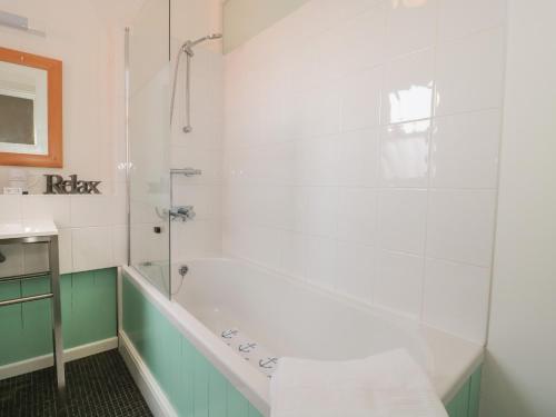 a white bathroom with a tub and a sink at Bluebell Apartment in Swanage