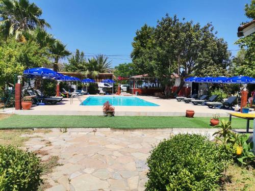 ein Pool mit blauen Sonnenschirmen und Gras in der Unterkunft Adrasan Maviay Hotel in Adrasan