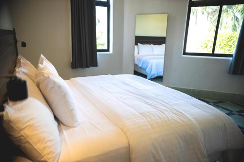 a large white bed in a bedroom with two windows at Hotel La Nacional By Kavia in Mérida