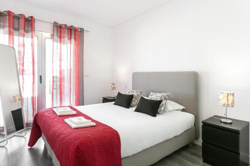 Un dormitorio con una gran cama blanca con una manta roja. en Just Sea, en Peniche