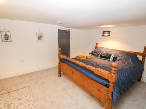 a bedroom with a wooden bed in a room at Rothlea Flat 1 in Pwllheli