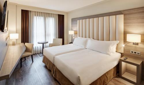 a hotel room with a large bed and a desk at Gran Hotel Luna de Granada in Granada