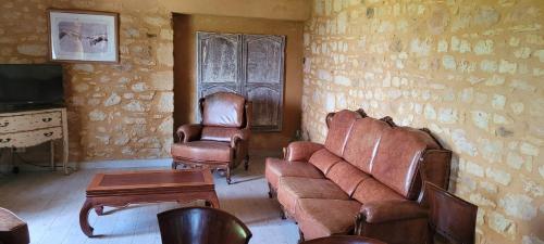 sala de estar con muebles de cuero, sofá y silla en La Clé des champs, Le Domaine de Brugal, en Carsac-Aillac