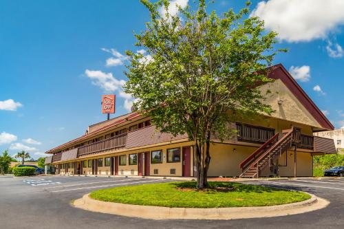 a building with a tree in front of it at Red Roof Inn Columbia East - Ft Jackson in Columbia