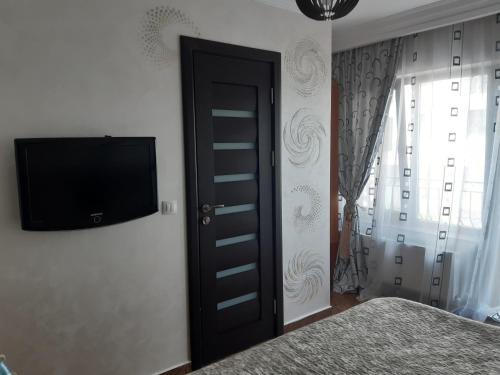 1 dormitorio con TV de pantalla plana en la pared en Casa Andrei en Năvodari