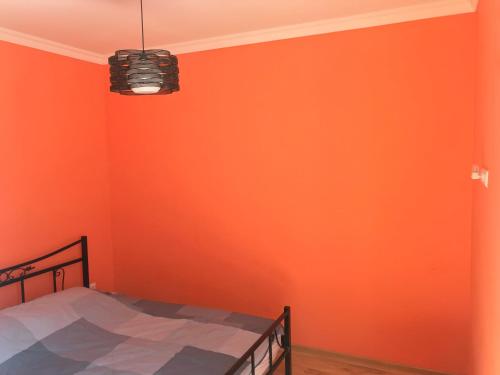 um quarto com uma parede laranja e uma cama em Apartment White Magnolia em Batumi