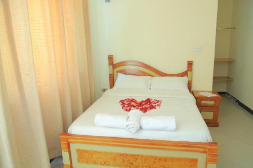 a bed with towels and a bouquet of flowers on it at Avi Guest House in Addis Ababa