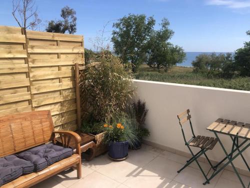 une terrasse avec un banc, une table et une chaise dans l'établissement Superbe studio front de mer - Pieds dans l’eau, à Linguizzetta