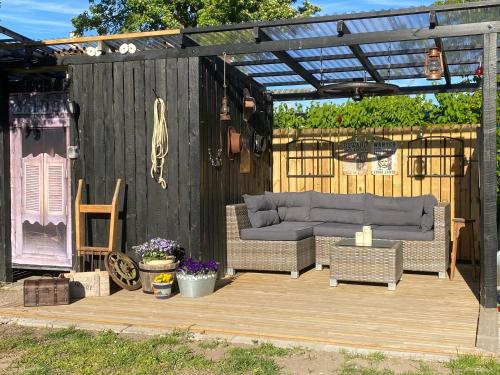 a wooden deck with a couch and a pergola at Piccobello Bed & Breakfast Valløby Køge in Valløby