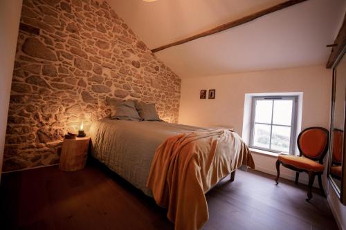 een slaapkamer met een bed en een stenen muur bij Proche PuyDuFou - Gite Maison La Roulière in Saint-Aubin-de-Baubigné