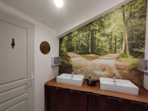 La salle de bains est pourvue de 2 lavabos et d'une peinture représentant une forêt. dans l'établissement Le refuge d'Athéna, à Chaussy