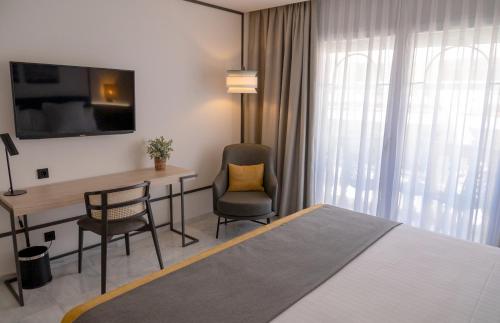 a hotel room with a bed and a desk and chair at URH Sitges Playa in Sitges