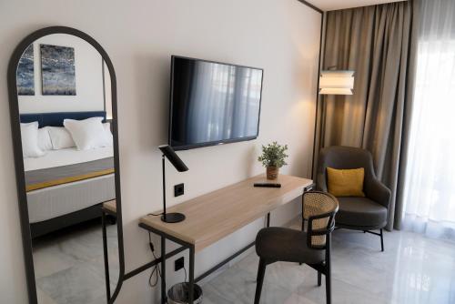 a room with a desk and a bed and a mirror at URH Sitges Playa in Sitges