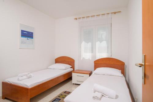twee bedden in een kamer met witte muren bij Apartman Karla in Trogir