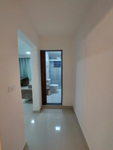 Cette chambre blanche dispose d'un miroir et d'une salle de bains. dans l'établissement Casa de Hóspedes em Parque Pinheiros - Sem Garagem, à Taboão da Serra