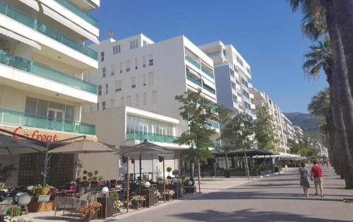 Twee mensen lopen over straat voor een gebouw. bij Enid Apartment in Vlorë