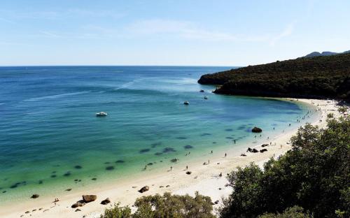 a beach with a bunch of people in the water at Perfect for quiet vacation with family and friends in Setúbal