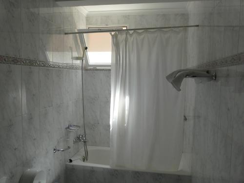 a bathroom with a shower curtain and a tub at Hotel Guillermo II in Mazarrón