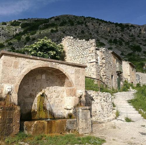 een oud stenen gebouw met een berg op de achtergrond bij Zia Elisa in Scanno