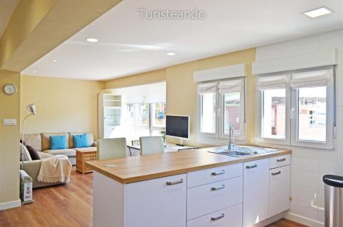 een keuken met witte kasten en een woonkamer bij Apartamento Marejada - Para amantes de la luz y las casas acogedoras in San Vicente de la Barquera