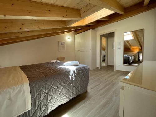 sypialnia z łóżkiem w pokoju z drewnianym sufitem w obiekcie Anfite Apartments Santa Maria w mieście Desenzano del Garda