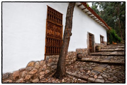 a tree next to a white building with stairs at Palacio Manco Capac by Ananay Hotels in Cusco