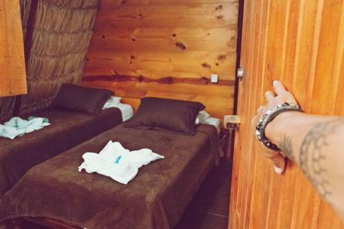 a person is pointing at two beds in a room at Raiz Kite Cabana in Jericoacoara