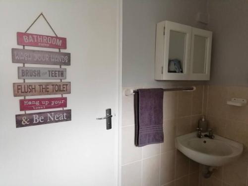 La salle de bains est pourvue d'un lavabo et d'une porte avec un panneau. dans l'établissement Charlotte's Web - Beach Cottage - Queensberry Bay, à East London