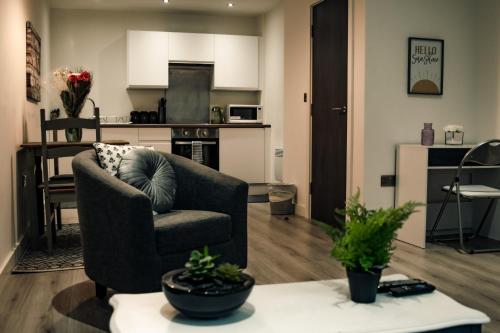 a living room with a chair and a kitchen at Bv Apartments Conditioning House Bradford in Bradford