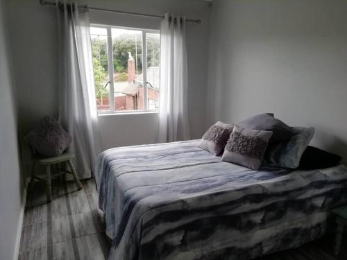 ein Bett in einem Schlafzimmer mit einem großen Fenster in der Unterkunft Charlotte's Web - Beach Cottage - Queensberry Bay in East London