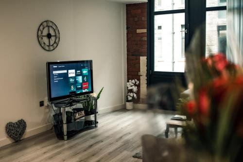 a living room with a television and a clock on the wall at Bv Apartments Conditioning House Bradford in Bradford