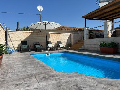 a swimming pool in a yard with chairs and an umbrella at MONTE AZUL in Málaga