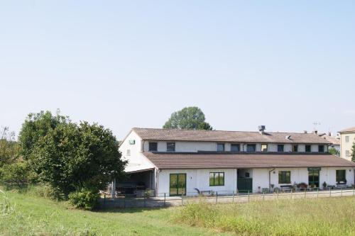 uma grande casa branca num campo relvado em Agriturismo La Valbona em San Martino Siccomario