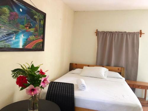 a bedroom with a bed and a table with a vase of flowers at Sunshine Hotel Little Corn Island in Little Corn Island