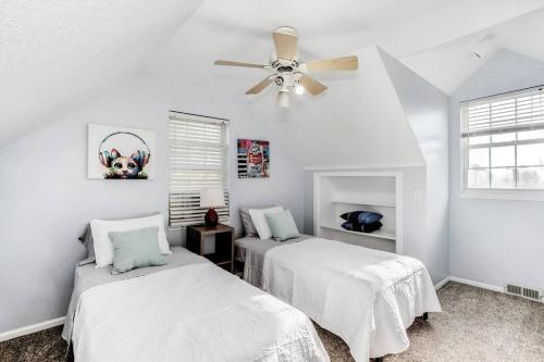 two beds in a white room with a ceiling fan at WOW! Spacious Retreat & amazing yard 2400+4bd/3bth in Wichita