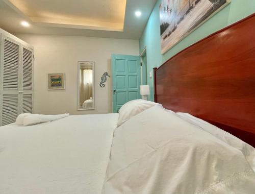 a bedroom with a large white bed with a wooden headboard at Seaside Villas in Caye Caulker