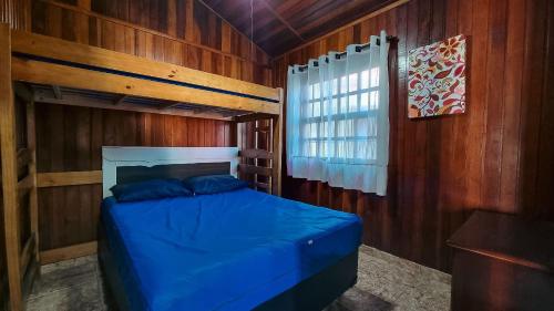 a bedroom with a blue bed in a wooden wall at Piscina Aquecida , SPA, Bilhar, Churrasqueira, Wi-Fi in Itanhaém