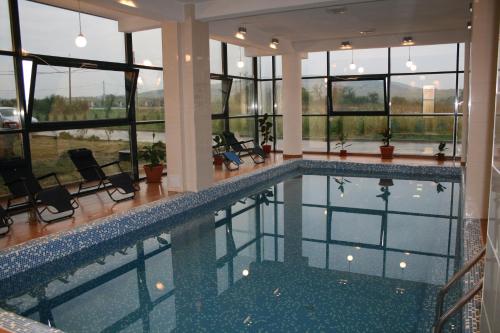 a large swimming pool in a building with windows at Hotel Hyperion in Baile Felix