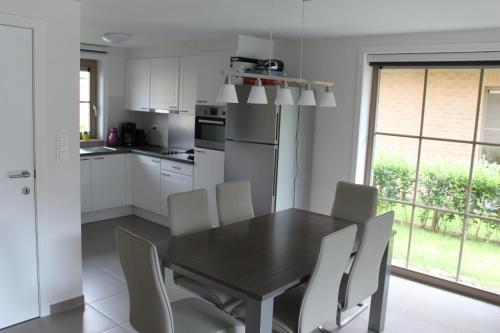 a kitchen with a black table and white chairs at Holiday Home Walhofpark 17 in Adinkerke