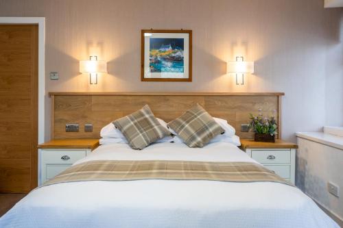 um quarto com uma grande cama branca e 2 almofadas em Riverside em Ullapool