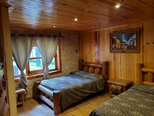 馬薩米特拉鎮的住宿－Cabaña DNellys Rosa con cancha de basquetbol，一间带两张床铺的卧室,位于带木墙的房间内