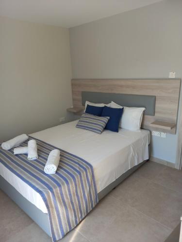 a bedroom with a large bed with blue and white pillows at Proteas Mare Suites in Protaras