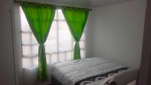 a bedroom with green curtains and a window at El mirador Raquireño ma in Ráquira