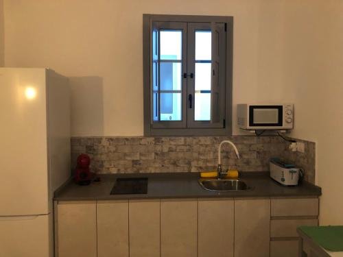 uma pequena cozinha com um lavatório e uma janela em Apartamentos Casa la Costanilla em Vejer de la Frontera