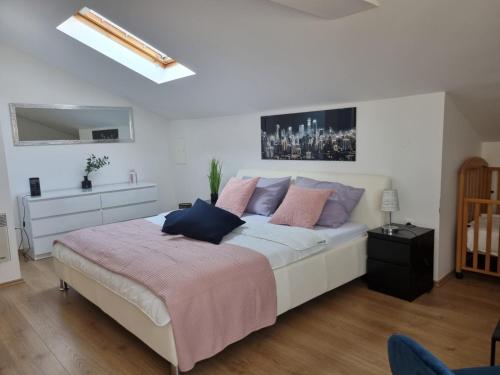 een slaapkamer met een groot wit bed met roze en blauwe kussens bij Apartman Petra s pogledom na more in Banjol