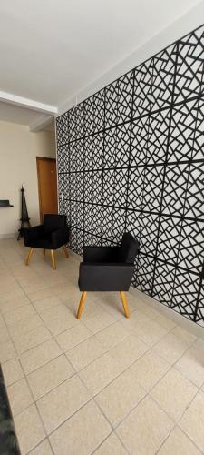 two black chairs in a room with a wall at Rio Quente Pousada do Charme in Rio Quente