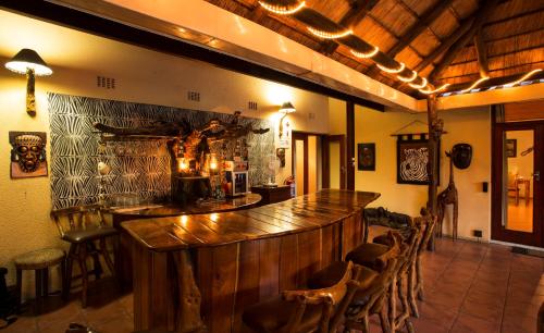 a bar with a wooden counter in a room with chairs at Sunbird Lodge in Phalaborwa