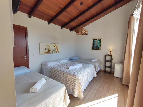 a bedroom with two beds and a wooden floor at Casa da Flôr GuestHouse, Praia Grande, Beto Carrero in Penha