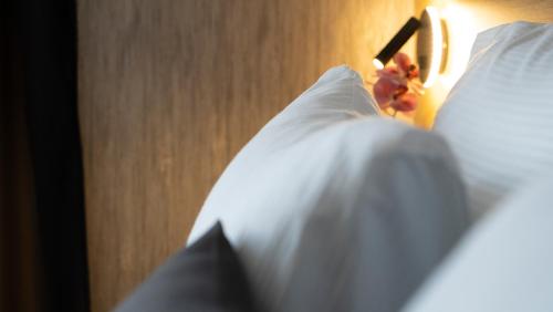 a close up of a bed with white sheets and a lamp at HA Hotel Mostar in Mostar